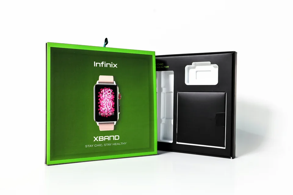 Infinix 智能手表包装盒实拍：绿色盒盖与黑色内部结构同时展示，盒内可见产品及配件分区。