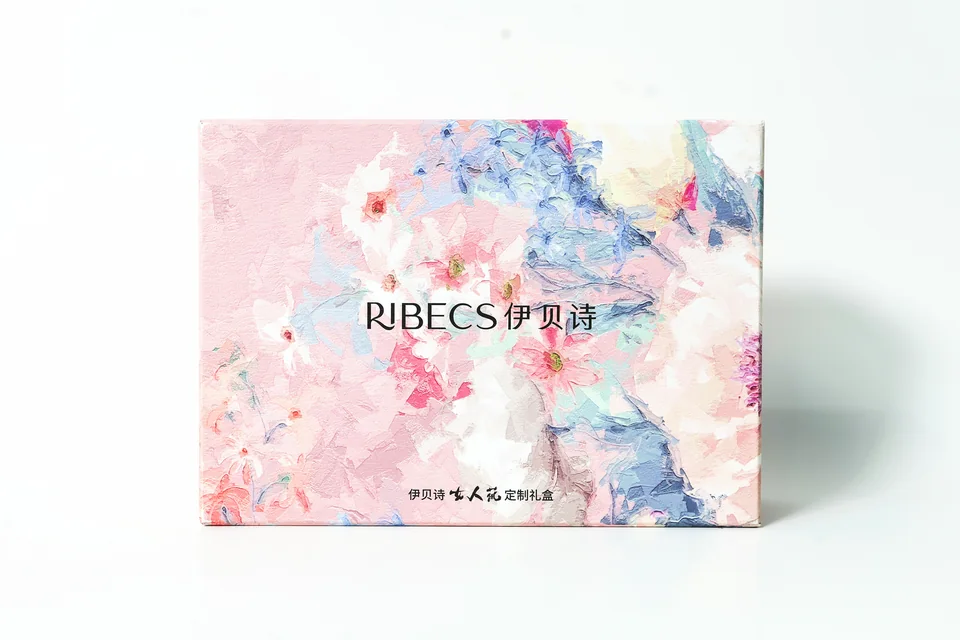 伊贝诗美妆定制礼盒实拍：礼盒正面以花卉图案和品牌文字展开，展示柔和配色的包装外观。